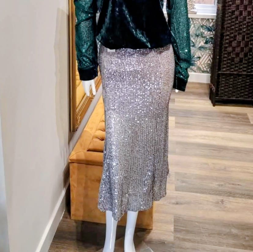 Mannequin wearing a sequin skirt and green jacket in a store setting

